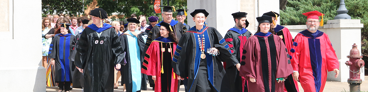 ECU faculty and honors students walk through columns.